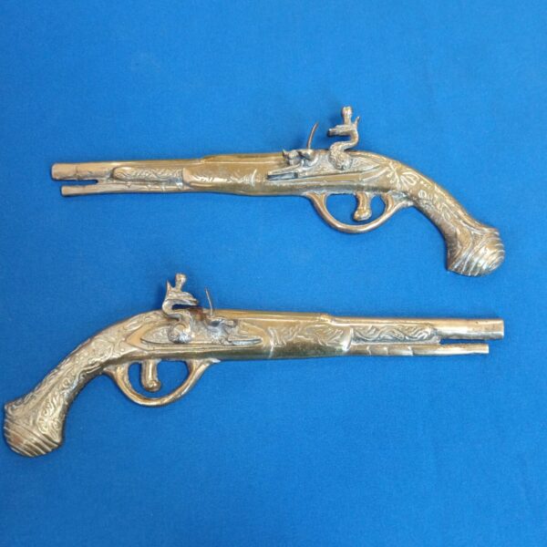 Pair of antique-style brass flintlock pistols for wall display.