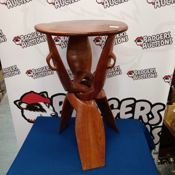 Vintage African tripod table with sculptural legs and dark wood.