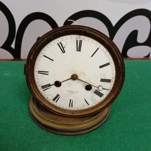Antique Rodier clock movement with enamel face and intricate detailing.
