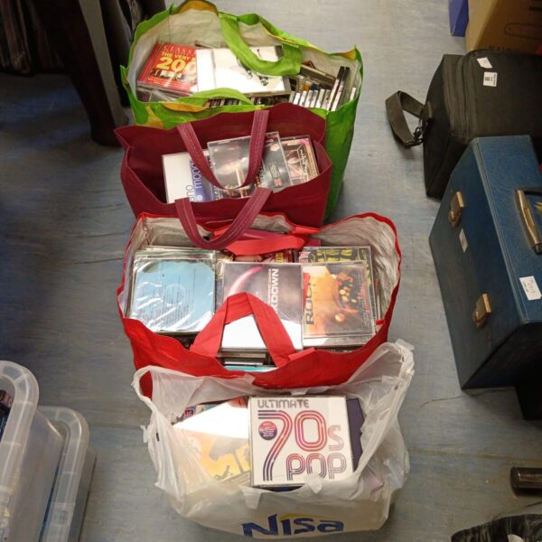 Four bags filled with a large collection of music CDs.