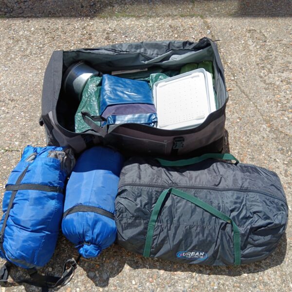 Camping gear bundle with tent and sleeping bags packed in a bag.