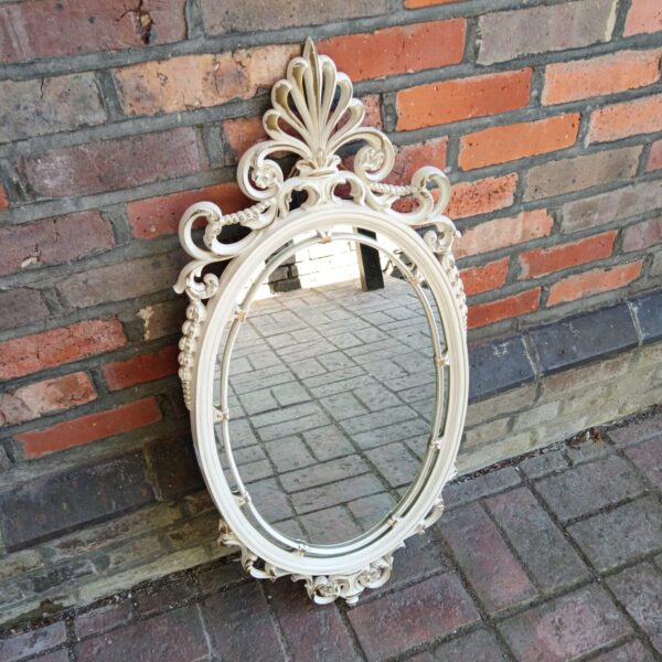Ornate vintage oval mirror in French style for wall decoration.