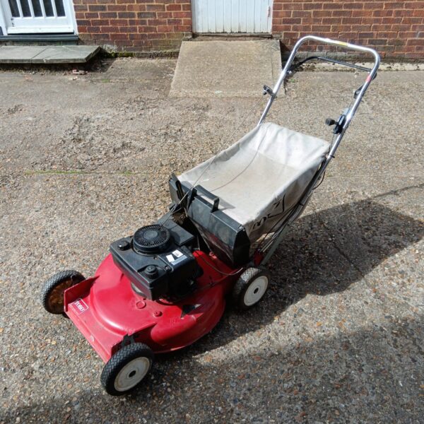 Red Toro petrol lawnmower in a garden setting.