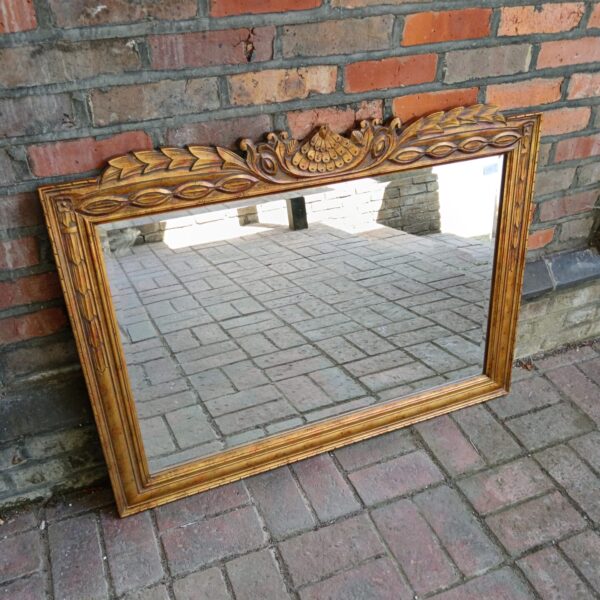Antique gilt overmantle mirror with bevelled edge and ornate frame.