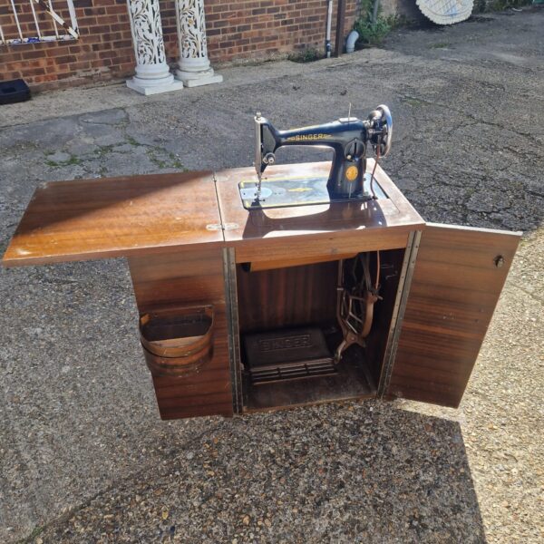 Vintage Singer sewing machine in wooden cabinet.