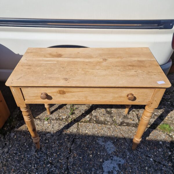 Rustic pine side table with a single drawer and turned legs.