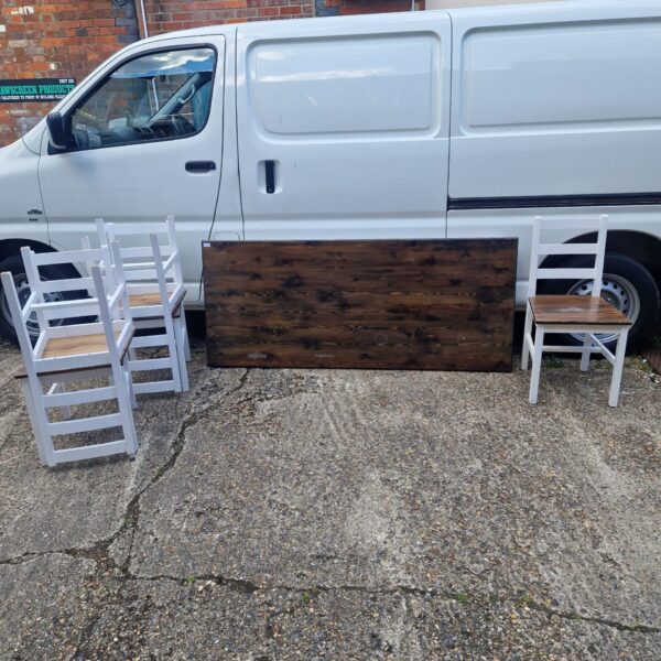 Rustic farmhouse dining set with white chairs and dark wood table.