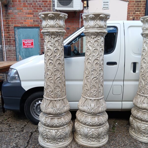 Pair of tall fibreglass decorative column plinths in a garden setting.