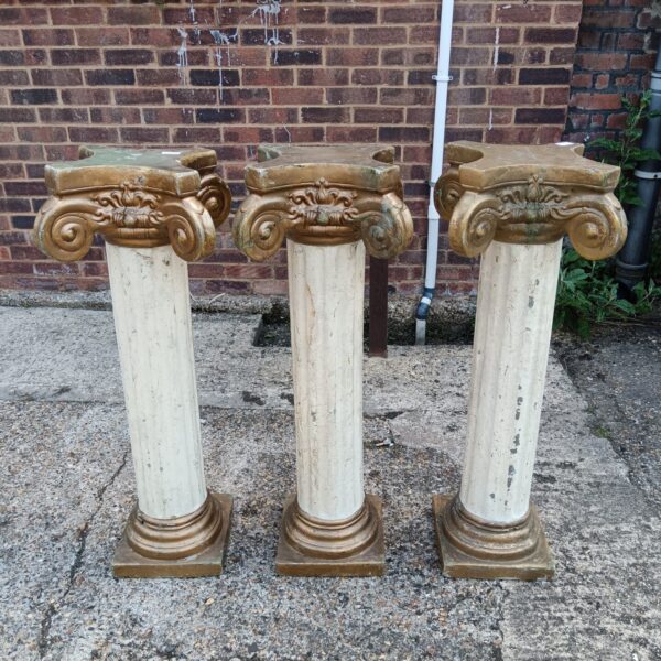 Three decorative fibreglass column plinths in a garden setting.