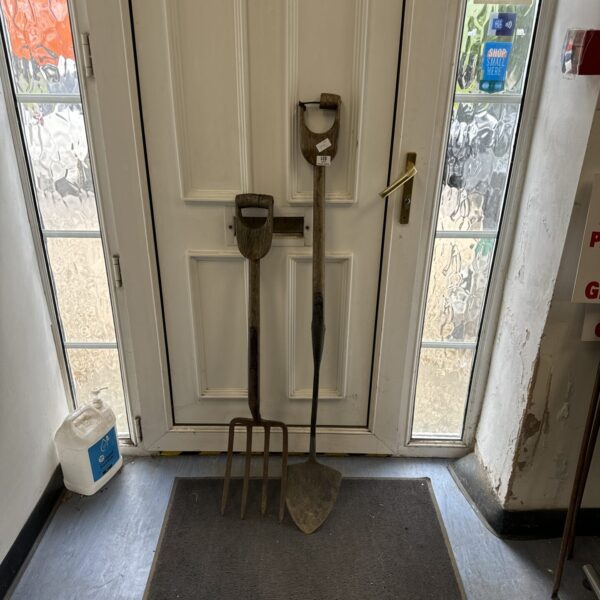 Vintage garden fork and spade leaning against a door.