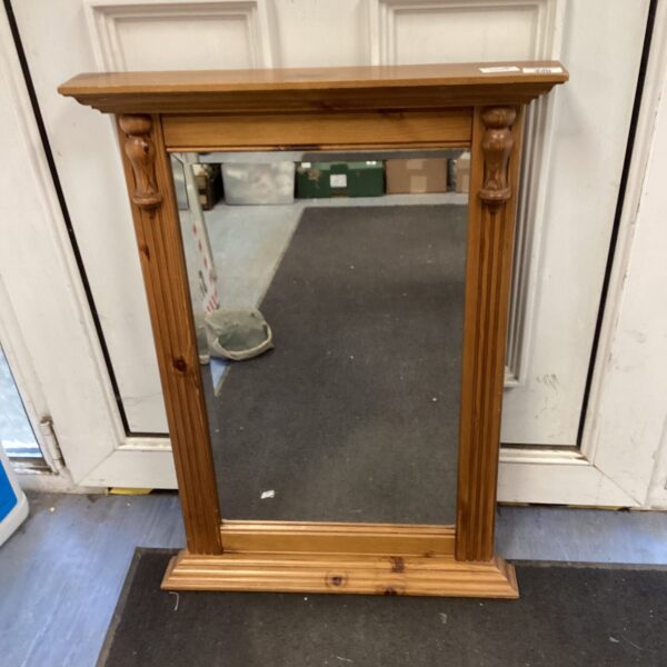 Vintage pine framed mirror with decorative moulding on a wall.