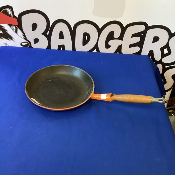 Vibrant red Le Creuset No 26 frying pan with a black handle.