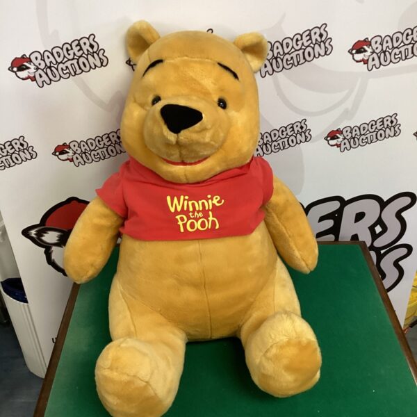 Large Winnie the Pooh plush toy, golden yellow, Disney character.