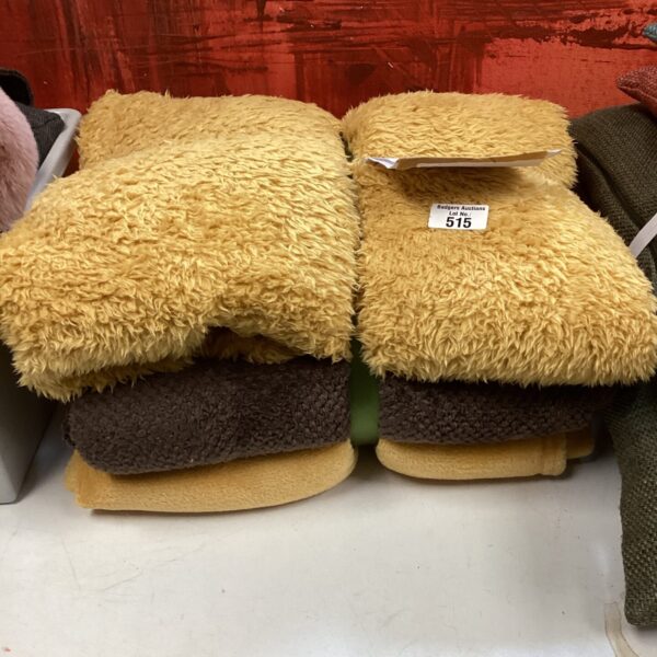 Lot of three fluffy throws in neutral tones.