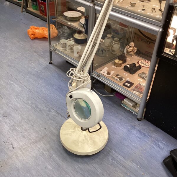 Vintage magnifying floor lamp with adjustable lens and metal base.