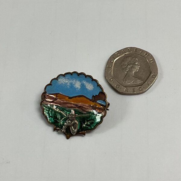 Close-up of a Victorian enamel pixie brooch on a dark surface.