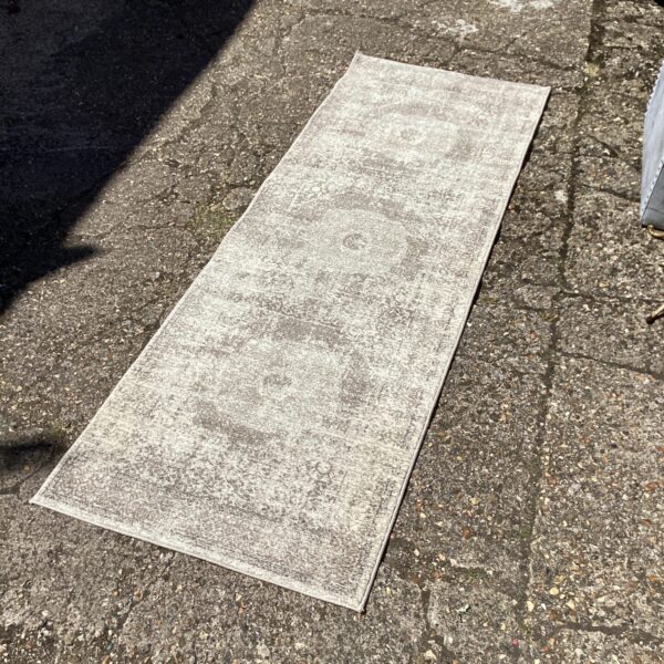 Faded vintage runner rug with patterned design.