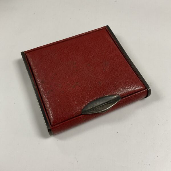 Antique silver cigarette case with red leather exterior.