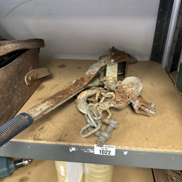 Vintage metal winch with chain and pulleys for lifting.