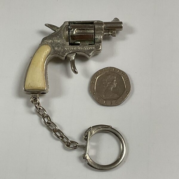 Vintage cap gun keyring with detailed miniature pistol.