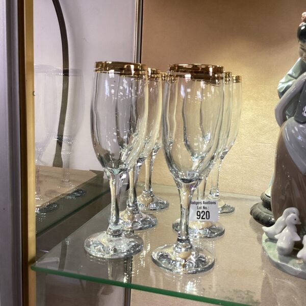 Six gilded champagne glasses in a display cabinet.