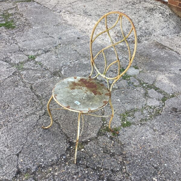 Antique wrought iron garden chair with weathered paint.