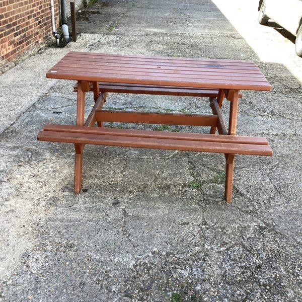 Weathered teak picnic bench in a garden setting.