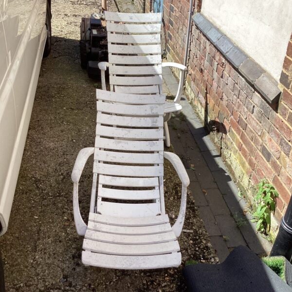 Weathered vintage reclining garden chair with wrought iron frame.