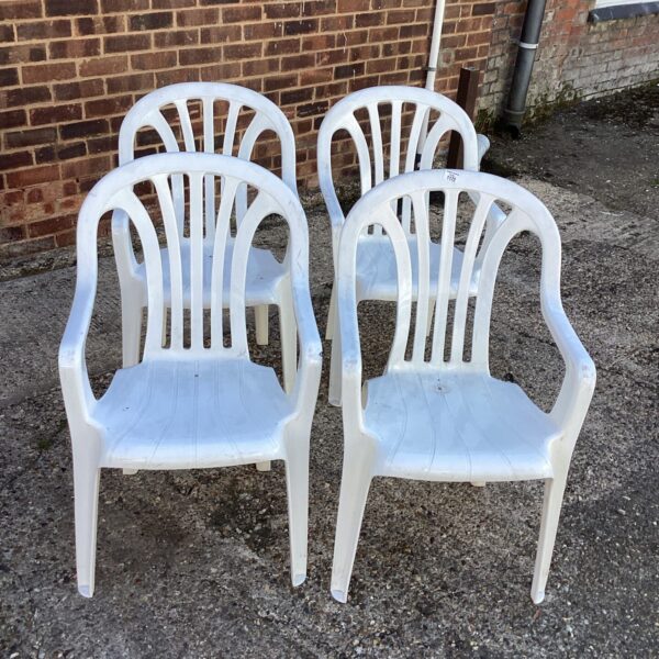 Set of four white plastic garden chairs for outdoor use.