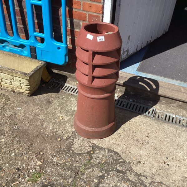 Vintage terracotta chimney pot in a garden setting.