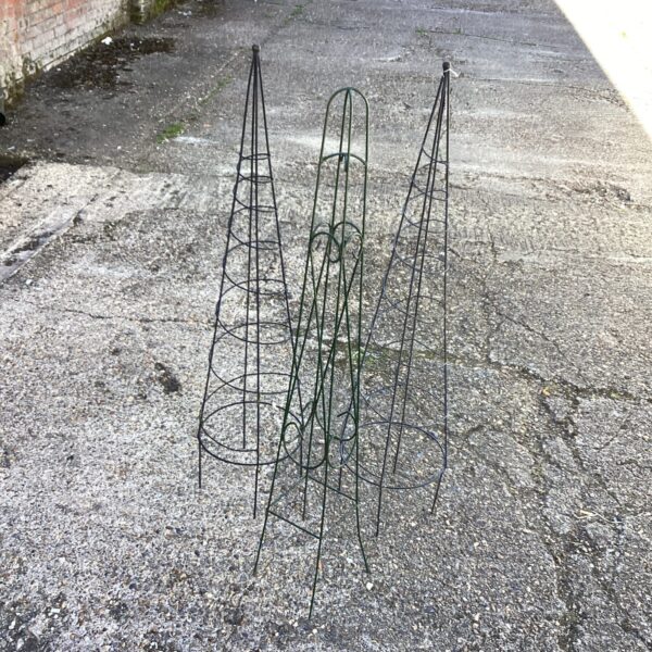 Three metal runner bean frames in a garden setting.