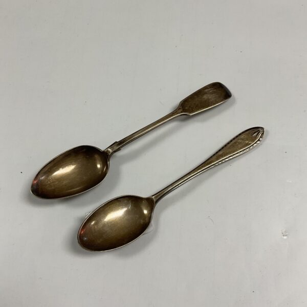 Pair of antique Victorian silver teaspoons on a white surface.