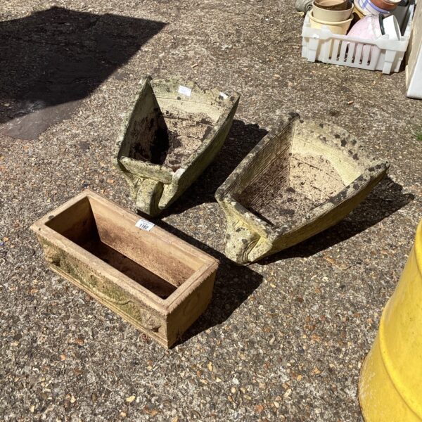 Weathered antique stone garden trough shaped like a wheelbarrow.