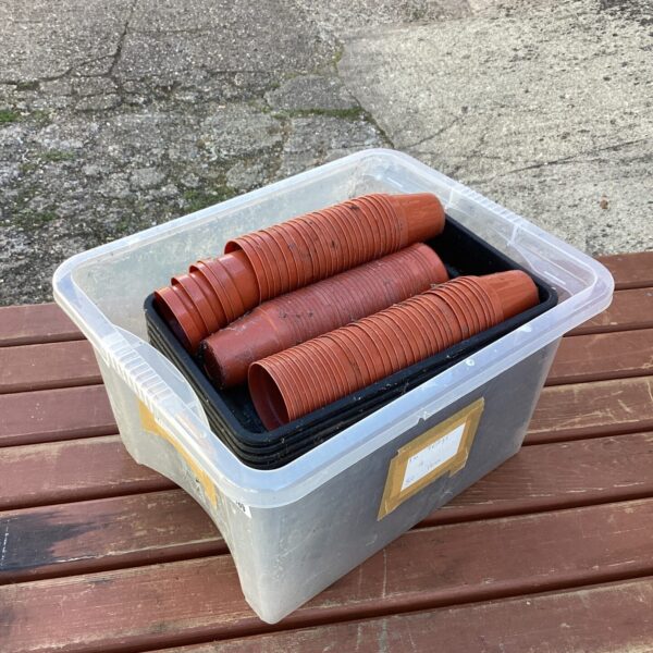 Stack of terracotta flower pots and plastic trays for gardening.
