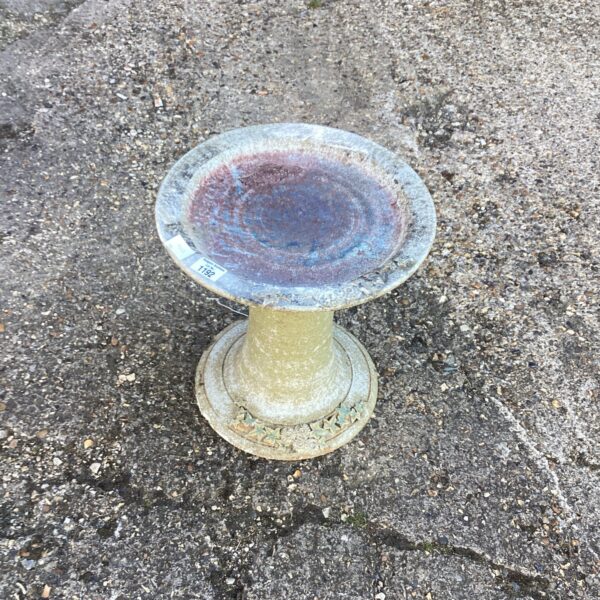 Weathered stone bird bath in a garden setting.