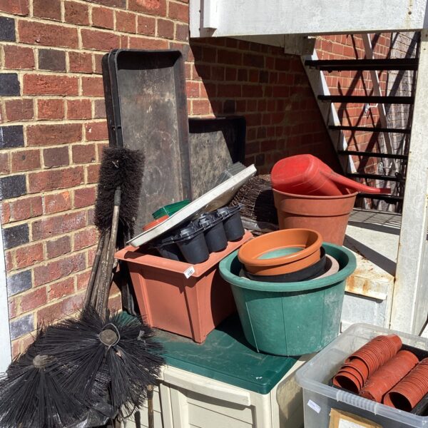 Lot of used garden pots and watering cans for outdoor gardening.