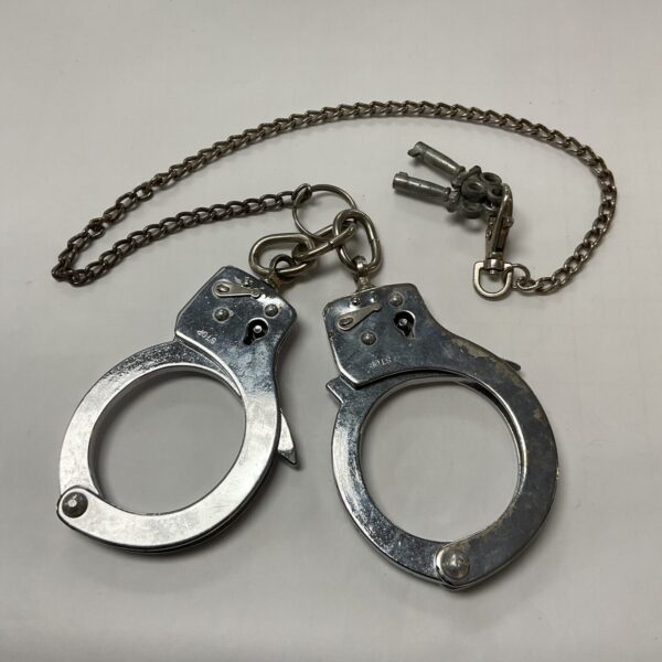 Vintage metal handcuffs with connecting chain, antique restraints.