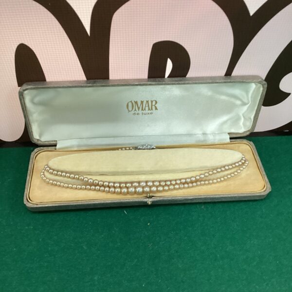 Vintage faux pearl necklace on a dark background.