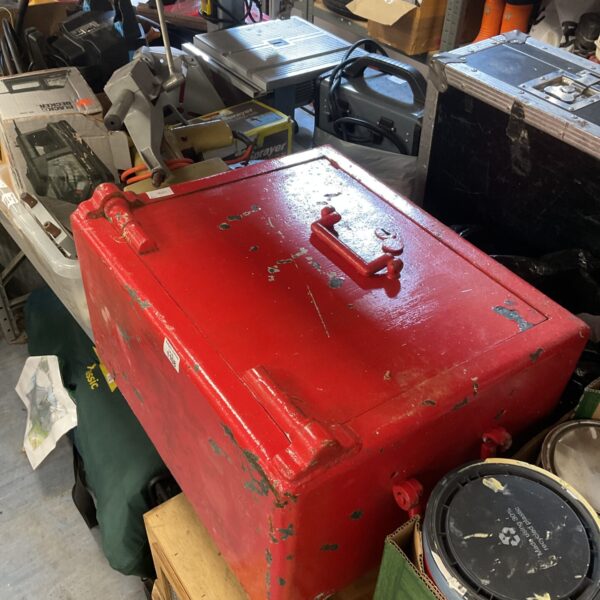 Vintage red metal strong box, locked for security.