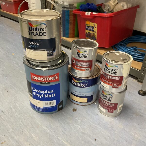 Collection of used Dulux Trade paint tins for DIY projects.
