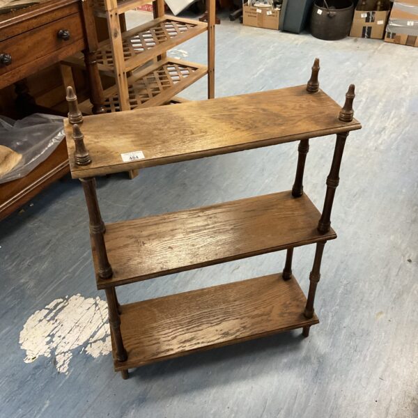 Vintage three-tier wooden bookshelf for displaying collectibles.