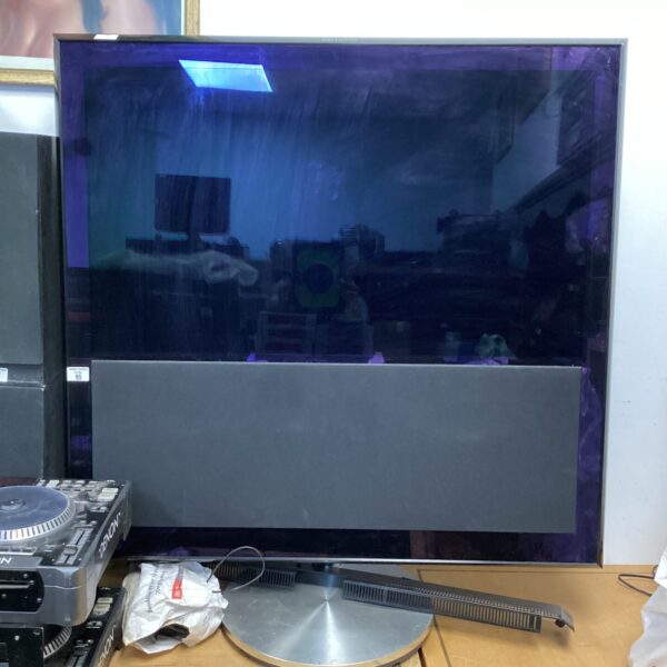 Bang & Olufsen BeoVision television with built-in soundbar and remotes.