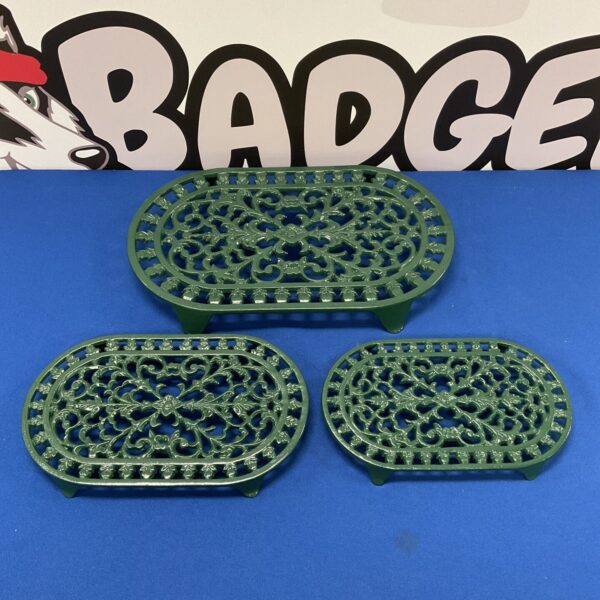 Set of three vintage cast iron trivets with ornate designs.