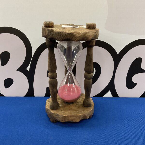Vintage pink sand hourglass on a wooden stand.