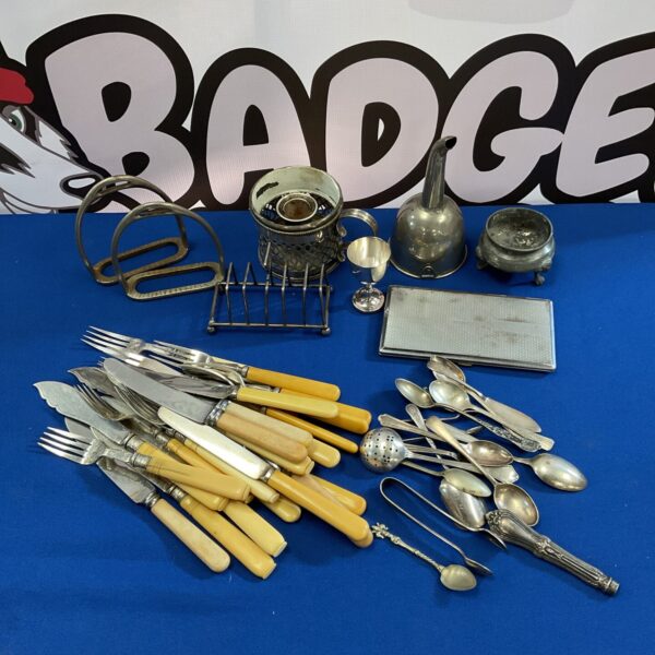 Vintage bone handled cutlery and mixed metalware lot on display.