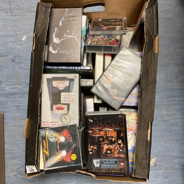 Mixed media collection of VHS tapes, DVDs, and CDs for collectors.