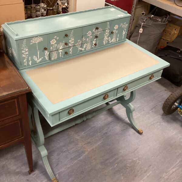 Turquoise floral writing desk with curved legs and painted details.