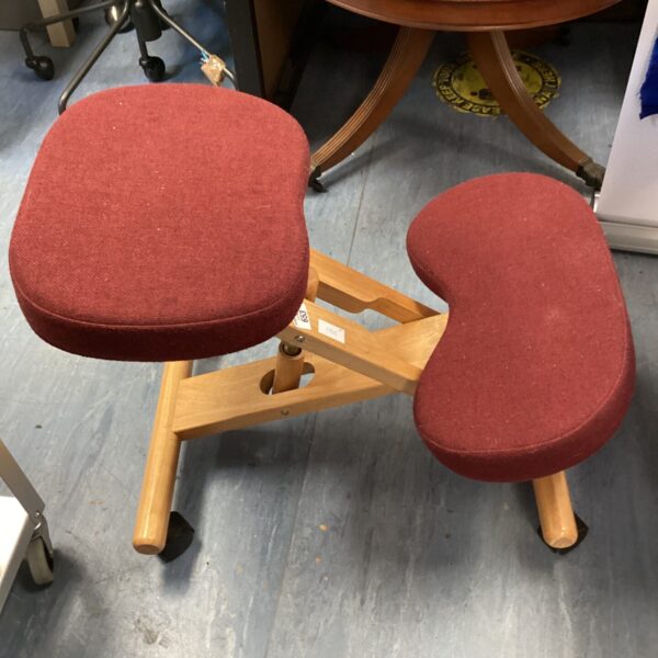 Red ergonomic kneeling chair with wooden frame and adjustable height.
