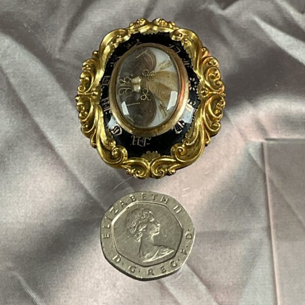 Antique Victorian mourning brooch with woven hair and black enamel.