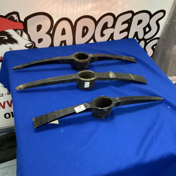Three vintage pickaxe heads showing wear and rust.